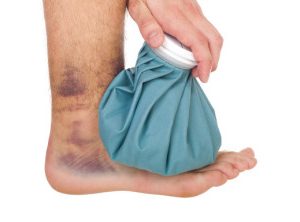young male icing a sprained ankle with ice pack (isolated on white background)